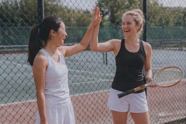 Two women celebrating with a high-five on a tennis court